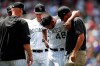 Colorado Rockies starting pitcher German Marquez, center, is tended to by trainer Keith Dugger, right, as shortstop Trevor Story looks on after Marquez was injured while warming up to face the Los Angeles Dodgers in the seventh inning of a baseball game Wednesday, July 31, 2019, in Denver. (AP Photo/David Zalubowski)