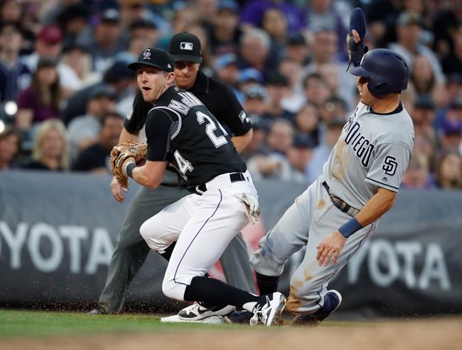 Colorado Rockies third baseman Ryan McMahon, left, forces out San Diego Padres' Ian Kinsler at third base, who was trying to advance on a bunt by Cal Quantrill during the fifth inning of a baseball game Friday, June 14, 2019, in Denver. (AP Photo/David Zalubowski)