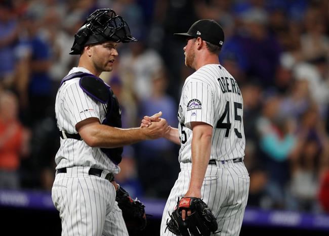 Colorado Rockies catcher Chris Iannetta, left, congratulates relief pitcher Scott Oberg, who stuck out Los Angeles Dodgers pinch-hitter Edwin Rios for the final out of a baseball game Friday, June 28, 2019, in Denver. The Rockies won 13-9. (AP Photo/David Zalubowski)