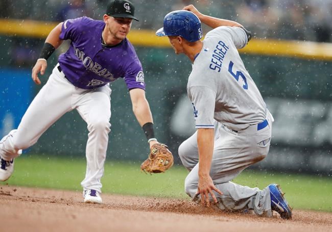 Colorado Rockies second baseman Ryan McMahon, left, turns to apply a late tag as Los Angeles Dodgers' Corey Seager advances to second base on a sacrifice fly hit by Justin Turner in the first inning of a baseball game Tuesday, July 30, 2019, in Denver. (AP Photo/David Zalubowski)