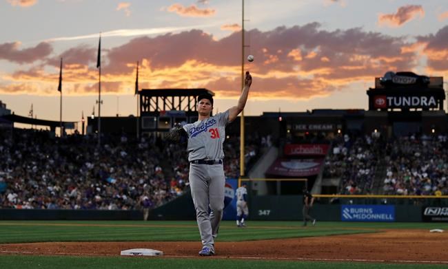 As the setting sun illuminates a cloud in the background, Los Angeles Dodgers first baseman Joc Pederson tosses a ball to a fan after infielders warmed up for the bottom of sixth inning of a baseball game against the Colorado Rockies on Thursday, June 27, 2019, in Denver. The Dodgers won 12-8. (AP Photo/David Zalubowski)