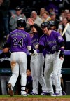 Colorado Rockies' Ryan McMahon (24) is congratulated at the plate by Trevor Story (27), Raimel Tapia and Nolan Arenado (28) after hitting a three-run home run off Philadelphia Phillies starting pitcher Zach Eflin during the sixth inning of a baseball game Thursday, April 18, 2019, in Denver. (AP Photo/Jack Dempsey)