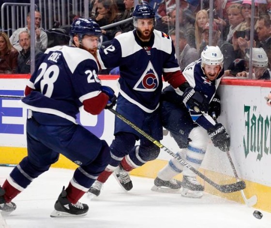 Winnipeg Jets center Bryan Little (18) tips the puck away from Colorado Avalanche defensemen Patrik Nemeth (12) and Ian Cole (28) during the first period of an NHL hockey game in Denver, Thursday, April 4, 2019. (AP Photo/Joe Mahoney)