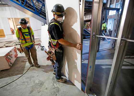 THE CANADIAN PRESS/Jeff McIntoshConstruction workers install sheets of drywall at a building project.