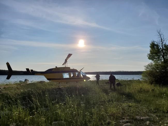 Officers look through a remote lake area alongside a landed helicopter in the Gillam, Man., area in July 28, 2019, police image published to social media. THE CANADIAN PRESS/HO-Twitter, Royal Canadian Mounted Police, @rcmpmb, *MANDATORY CREDIT*