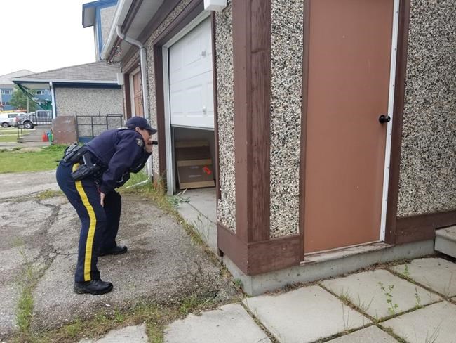 An RCMP officer shines a light into an open garage at a home in the Gillam, Man., area in July 27, 2019, police image published to social media. THE CANADIAN PRESS/HO-Twitter, Royal Canadian Mounted Police, @rcmpmb, *MANDATORY CREDIT*