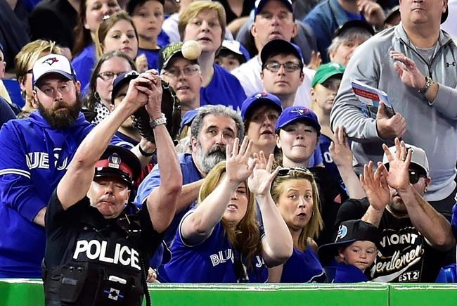 In this May 14, 2017, file photo, a police officer tries to catch a foul ball during seventh inning of a baseball game between the Toronto Blue Jays and Seattle Mariners in Toronto. The Toronto Blue Jays say they will extend the protective netting at the Rogers Centre and Dunedin Stadium ??? their home for spring training in Florida ??? next season. THE CANADIAN PRESS/Frank Gunn