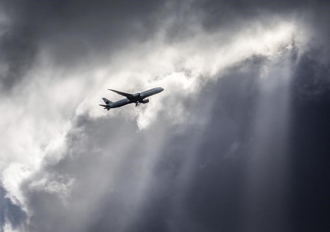 An Air Canada plane flies underneath dark clouds illuminated by some sun rays above Frankfurt, Germany, Thursday, March 2, 2017. Air Canada says it has suspended service to India as tensions mount between that country and Pakistan. THE CANADIAN PRESS/AP-Frank Rumpenhorst/dpa via AP