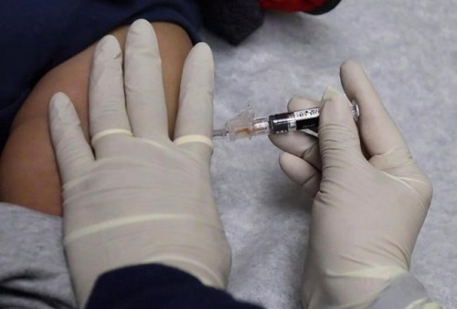 A medical assistant at the Sea Mar Community Health Center gives a patient a flu shot in Seattle on January 11, 2018. THE CANADIAN PRESS/AP/Ted S. Warren