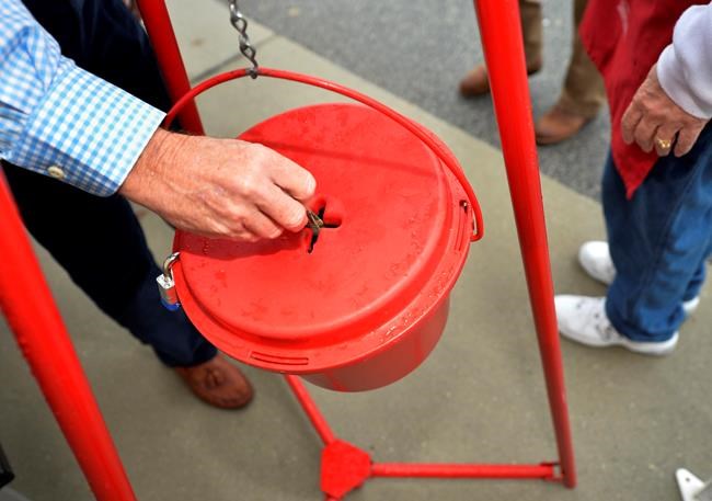In this Nov. 9, 2018, file photo money gets dropped into the kettle during the Annual Salvation Army Red Kettle and Angel Tree Kick Off outside the Hobby Lobby store in Augusta, Ga. Canada's Salvation Army is testing out a new and faster way to allow cashless donations to its kettle stations via debit and credit card, making the process as quick and easy as dropping a toonie in the bubble. THE CANADIAN PRESS/AP-Michael Holahan/The Augusta Chronicle via AP, File