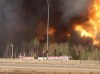 Trees burn near a road in Fort McMurray, Alberta on Tuesday May 3, 2016 in this image provide by radio station CAOS91.1. At least half of the city of Fort McMurray in northern Alberta was under an evacuation notice Tuesday as a wildfire whipped by winds engulfed homes and sent ash raining down on residents. THE CANADIAN PRESS/HO-CAOS91.1(KAOS)