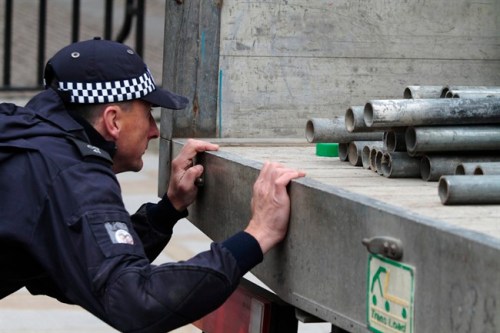 Policing the royal visit of the Duke and Duchess of Cambridge will be a balancing act that will be on almost continuous display over the nine-day Canadian tour, which gets underway on Thursday. As part of security preparations for the royal wedding of Prince William and Kate Middleton, a British police officer is shown inspecting tubes to be used to built a scaffolded stage reserved for media, outside the Westminster Abbey, in central London, Tuesday, April 26, 2011. THE CANADIAN PRESS/AP-Lefteris Pitarakis