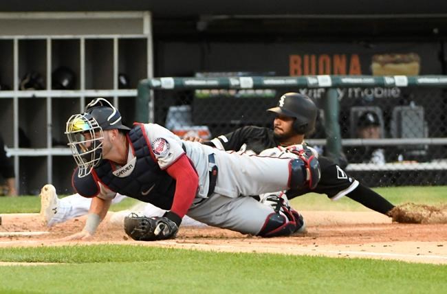 Chicago White Sox's Jose Rondon, back, is safe at home as Minnesota Twins catcher Mitch Garver, front, can't handle an errant throw during the second inning of a baseball game, Saturday, July 27, 2019, in Chicago. (AP Photo/David Banks)