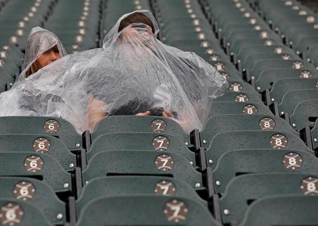 Fans shelter under ponchos during a rain delay of a baseball game between the Chicago White Sox and the Kansas City Royals, Monday, May 27, 2019, in Chicago. (AP Photo/Jim Young)