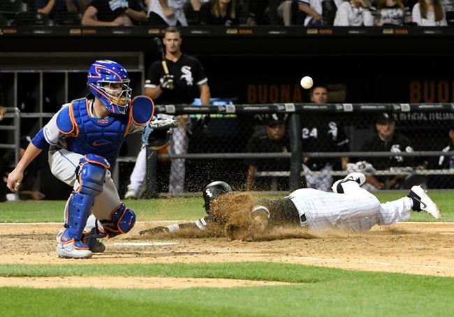 Chicago White Sox's Ryan Goins, right, scores as New York Mets catcher Tomas Nido waits for the throw during the ninth inning of a baseball game, Tuesday, July 30, 2019, in Chicago. (AP Photo/David Banks)