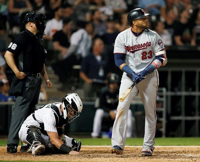 Minnesota Twins' Nelson Cruz (23), right, watches his solo home run during seventh inning of a baseball game as Chicago White Sox catcher James McCann, center, and home plate umpire Chris Segal, left, look on Friday, July 26, 2019, in Chicago. (AP Photo/Jeff Haynes)