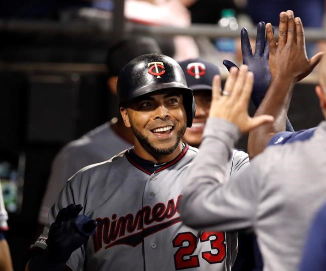 Minnesota Twins' Nelson Cruz celebrates with teammates in the dugout after hitting a solo home run during seventh inning of a baseball game against the Chicago White Sox, Friday, July 26, 2019, in Chicago. (AP Photo/Jeff Haynes)