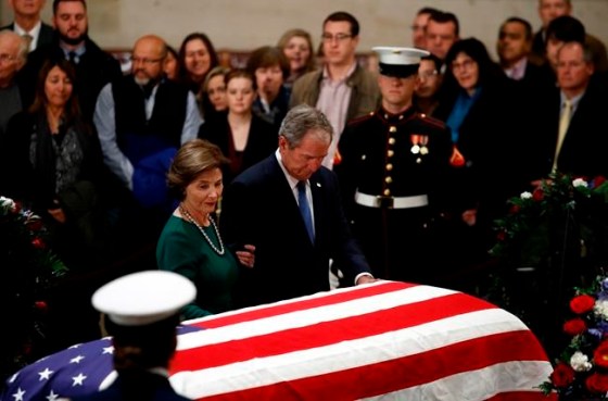 Former President George W. Bush and former first lady Laura Bush pause in front of the flag-draped casket of former President George H.W. Bush as he lies in state in the Capitol's Rotunda in Washington, Tuesday, Dec. 4, 2018. (AP Photo/Patrick Semansky)