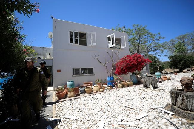 Israeli soldiers walk by a house hit by a rocket fired from Gaza in a moshav in Israel near the border with Gaza, Saturday, May 4, 2019. Palestinian militants in the Gaza Strip fired at least 90 rockets into southern Israel on Saturday, according to the Israeli military, triggering retaliatory airstrikes and tank fire against militant targets in the blockaded enclave and shattering a month-long lull in violence. (AP Photo/Tsafrir Abayov)