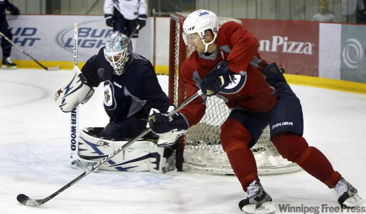 Wayne Glowacki / Winnipeg Free Press
Winnipeg Jet Eric Fehr (red jersey) sweeps around Jets goalie Chris Mason at the MTS Iceplex, practising with his teammates.