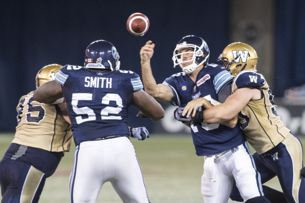 Chris Young / The Canadian Press 
Toronto Argonauts quarter back Rickie Ray (centre right) makes a pass despite being tackled by Winnipeg Blue Bombers Greg Peach during first half CFL football action in Toronto on Tuesday.