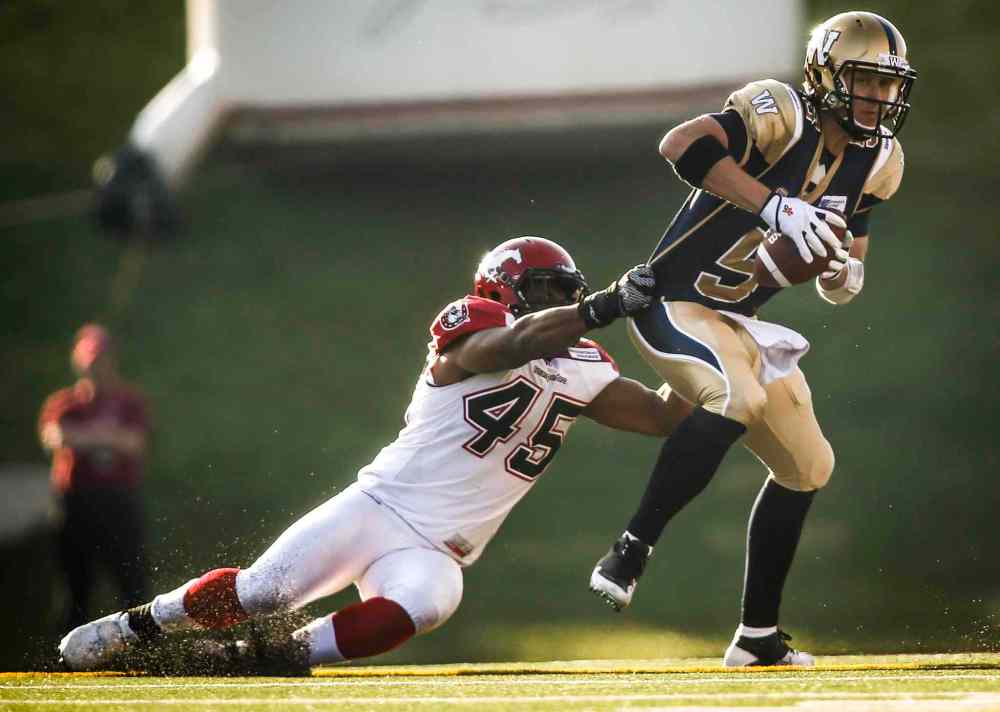 Jeff McIntosh / The Canadian Press
Winnipeg Blue Bombers' quarterback Drew Willy, right, gets sacked by Calgary Stampeders' Karl McCartney during CFL pre-season football action in Calgary on Saturday. The Stampeders won 23-20.