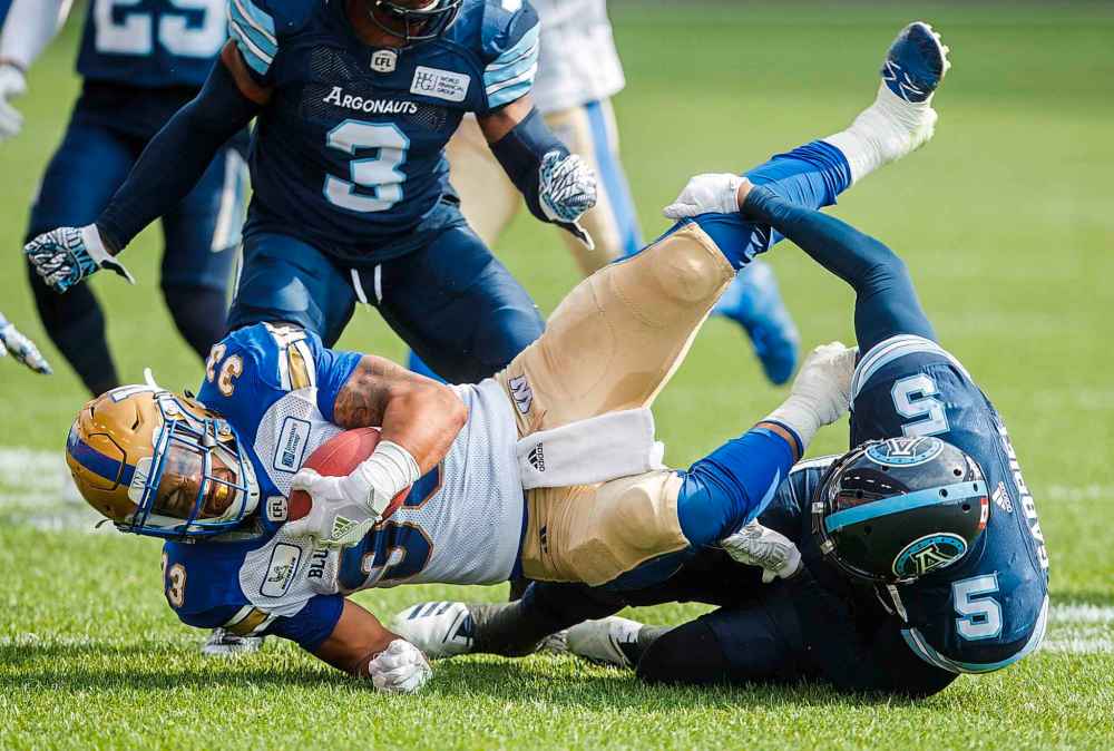 Winnipeg Blue Bombers Andrew Harris, left, runs the ball against Toronto Argonauts' Jermaine Gabriel, right, during the first half of CFL football action in Toronto, Saturday July 21, 2018.