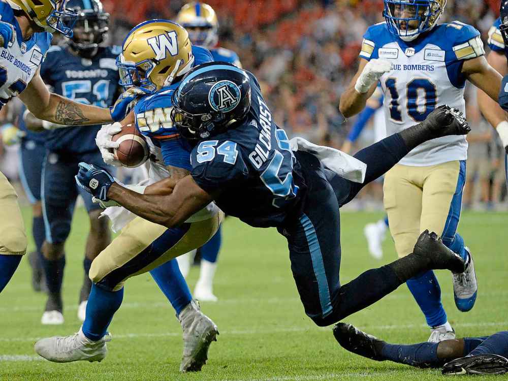 NATHAN DENETTE / THE CANADIAN PRESS
Toronto Argonauts linebacker Kennan Gilchrist (54) stops Winnipeg Blue Bombers running back Andrew Harris (33) during second half.