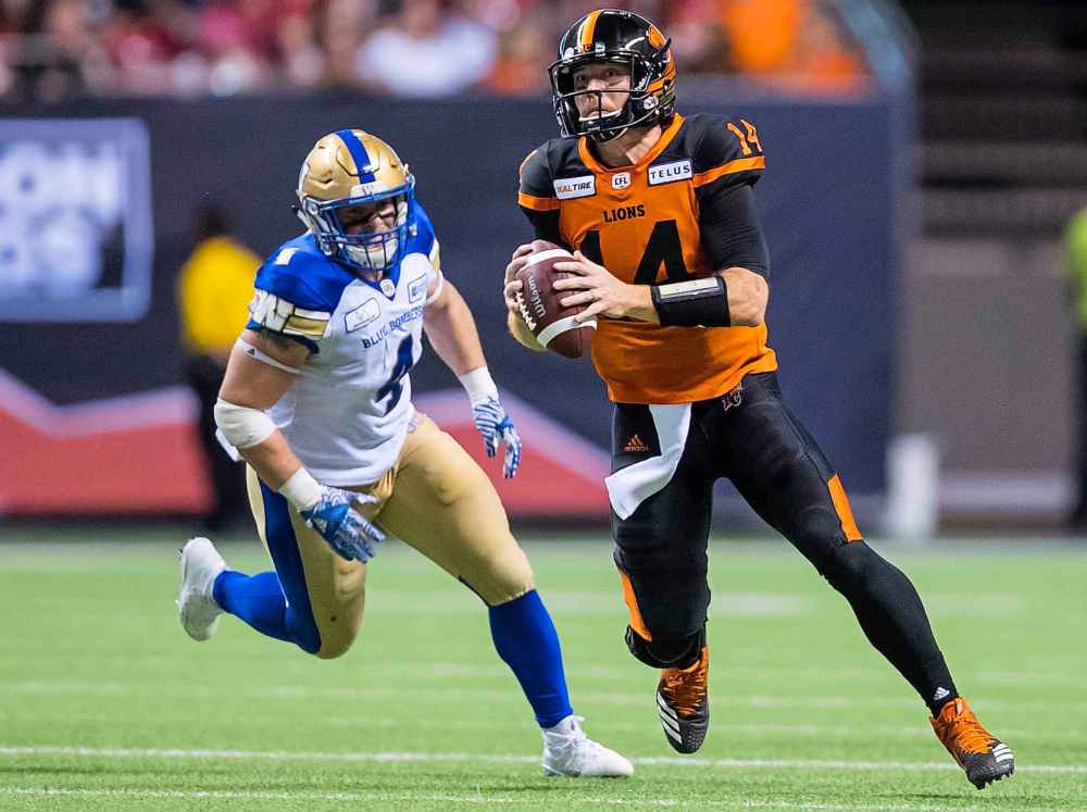 DARRYL DYCK / The Canadian Press
B.C. Lions quarterback Travis Lulay, right, is chased by Winnipeg Blue Bombers' Adam Bighill before completing a pass to Bryan Burnham during the second half.