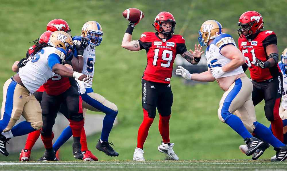 JEFF MCINTOSH / THE CANADIAN PRESS
Winnipeg Blue Bombers' pressure Calgary Stampeders quarterback Bo Levi Mitchell, centre, as he throws the ball during second quarter CFL football action in Calgary, Saturday, Aug. 25, 2018.