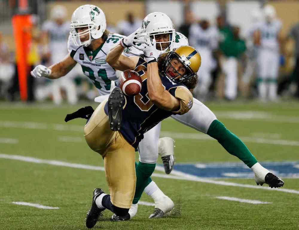 John Woods / The Canadian Press
Winnipeg Blue Bombers' Julian Feoli-Gudino (83) can't hang onto the ball with pressure from Saskatchewan Roughriders' Tyron Brackenridge (41) and Samual Hurl (31) during the second half of CFL action in Winnipeg Thursday, August 7, 2014.