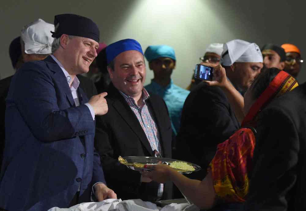 SEAN KILPATRICK / THE CANADIAN PRESS
Conservative Leader Stephen Harper and Tory candidate Jason Kenney serve food at the Gursikh Sabha Canada temple Wednesday in Scarborough, Ont.