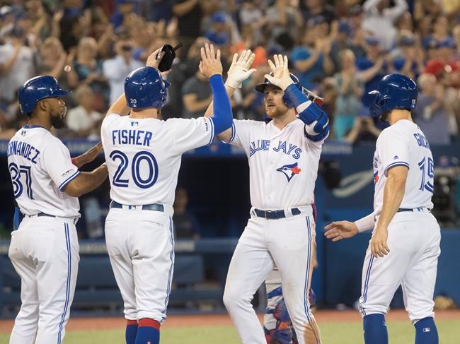 Toronto Blue Jays' Brandon Drury is met by teammates at home plate after hitting a grand slam during fourth inning American League MLB baseball action against the Texas Rangers, in Toronto, Monday, Aug. 12, 2019. THE CANADIAN PRESS/Fred Thornhill