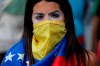 An anti-government protester wears a Venezuelan flag to cover her face, after a rally demanding the resignation of President Nicolas Maduro in Caracas, Venezuela, Wednesday, Jan. 23, 2019. The head of Venezuela's opposition-run congress declared himself interim president at the rally, until new elections can be called. (AP Photo/Fernando Llano)