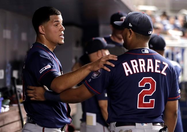 Minnesota Twins starting pitcher Jose Berrios, left, talks with second baseman Luis Arraez (2) after being removed during the seventh inning of the team's baseball game against the Miami Marlins, Wednesday, July 31, 2019, in Miami. The Twins won 7-4. (AP Photo/Lynne Sladky)
