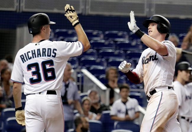Miami Marlins' Garrett Cooper, right, is met by Trevor Richards (36) after scoring on a three-run home hit by Cooper in the sixth inning of a baseball game against the San Francisco Giants, Tuesday, May 28, 2019, in Miami. (AP Photo/Lynne Sladky)