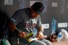 Arizona Diamondbacks' Yasmany Tomas brushes off a bat while sitting in the dugout during the fifth inning of a baseball game against the Miami Marlins, Friday, July 26, 2019, in Miami. The 28-year-old outfielder was brought back from the minor leagues by the Diamondbacks on Friday. (AP Photo/Wilfredo Lee)