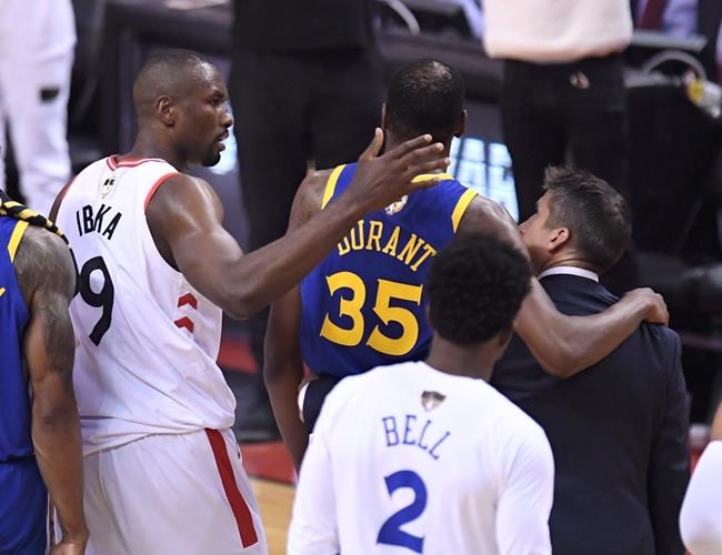 Toronto Raptors centre Serge Ibaka (9) consoles Golden State Warriors forward Kevin Durant (35) as he leaves the game with a leg injury during first half basketball action in Game 5 of the NBA Finals in Toronto on Monday, June 10, 2019. THE CANADIAN PRESS/Frank Gunn