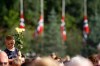 A boy holds up flowers as Norwegian flags fly at half-mast during a vigil in memory of the eight people killed in Friday's blast in Oslo and the 68 who died in the shooting at the youth camp on Utoya, in Vik, near Sundvollen, close to Utoya island, near Oslo, Norway, Tuesday, July 26, 2011. (AP Photo/Ferdinand Ostrop)