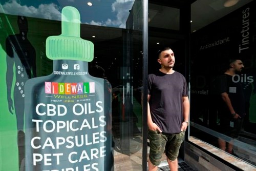 In this photo taken Thursday, March 21, 2019, Gus Dabais stands outside his Sidewalk Wellness store in San Francisco. CBD oil-infused food, drinks and dietary supplements are popular even though the U.S. government says they're illegal and some local authorities have forced retailers to pull products. The confusion has California, Texas and other states moving to legalize the cannabis compound that many see as beneficial to their health. (AP Photo/Eric Risberg)