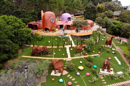 This Monday, April 1, 2019 photo, shows an aerial view of the Flintstone House in Hillsborough, Calif. The San Francisco Bay Area suburb of Hillsborough is suing the owner of the house, saying that she installed dangerous steps, dinosaurs and other Flintstone-era figurines without necessary permits. The owner and her attorney say they will fight for the rights of property owners and Fred and Barney fans everywhere. (AP Photo/Terry Chea)