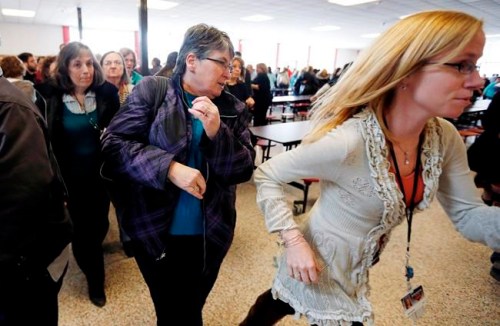 FILE - In this March 15, 2013, file photo, participants rush out of the cafeteria after hearing gun shots during a lockdown exercise at Milford High School in Milford, Mass. The actions of students who died tackling gunmen at two separate U.S. campuses a week apart have been hailed as heroic. At a growing number of schools around the country, they also reflect guidance to students who are told, at least in some situations, to do what they can to disrupt shootings. (AP Photo/Michael Dwyer, File)