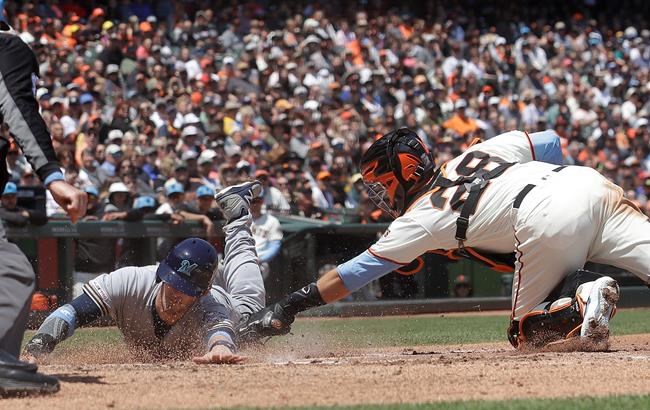 San Francisco Giants catcher Buster Posey (28) tags out Milwaukee Brewers' Yasmani Grandal at home during the third inning of a baseball game in San Francisco, Sunday, June 16, 2019. (AP Photo/Jeff Chiu)
