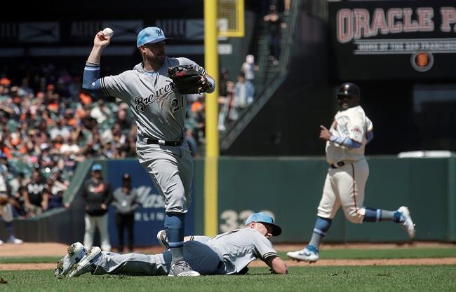 Milwaukee Brewers third baseman Travis Shaw, top left, throws over pitcher Chase Anderson while fielding a bunt by San Francisco Giants' Mike Yastrzemski as Pablo Sandoval, back right, advances to third base during the fifth inning of a baseball game in San Francisco, Sunday, June 16, 2019. Yastrzemski reached first base safely. (AP Photo/Jeff Chiu)