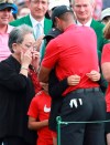 Tiger Woods' mother Kultida Woods wipes away tears as he hugs his daughter Sam and son Charlie behind the 18th green after winning the Masters at Augusta National Golf Club on Sunday, April 14, 2019, in Augusta. (Curtis Compton/Atlanta Journal-Constitution via AP)