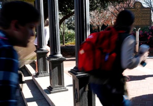 FILE- In this Jan. 9, 2019, file photo University of Georgia undergraduate students avoid walking under the university arch on the first day of the spring semester in Athens, Ga. At orientation every UGA student is told if they walk under the arch before they finished their degree they will never graduate. Forty percent of students who enroll in a four-year college don‚Äôt graduate within six years, according to the National Center for Education Statistics. (Joshua L. Jones/Athens Banner-Herald via AP)
