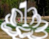 Alice Hewson is seen through the logo of the Augusta National Women's Amateur golf tournament as she hits off the fairway of the 18th hole during the tournament's first round at Champions Retreat in Evans, Ga., Wednesday, April 3, 2019. (AP Photo/David Goldman)
