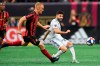 CORRECTS ID TO DEFENSEMAN JEFF LARENTOWICZ, NOT FORWARD HECTOR VILLALBA - Atlanta United defenseman Jeff Larentowicz, left, defends a kick by New England Revolution midfielder Carles Gil during the first half of an MLS Cup playoff soccer game Saturday, Oct. 19, 2019, in Atlanta. (AP Photo/John Amis)