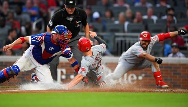 Cincinnati Reds' Kyle Farmer scores as Atlanta Braves catcher Tyler Flowers, left, tries to tag him on a sacrifice fly by Joey Votto during the fourth inning of a baseball game Friday, Aug. 2, 2019, in Atlanta. (AP Photo/John Amis)