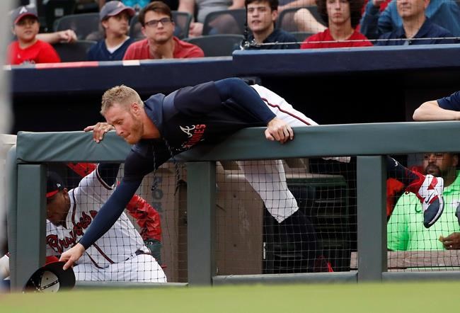 Atlanta Braves starting pitcher Mike Foltynewicz reaches over the dugout railing for a foul ball in the first inning of a baseball game against the New York Mets Tuesday, June 18, 2019, in Atlanta. Foltynewicz was not in the starting lineup. (AP Photo/John Bazemore)